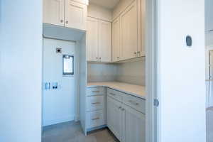 Kitchen featuring light stone countertops, white cabinetry, and light tile patterned flooring
