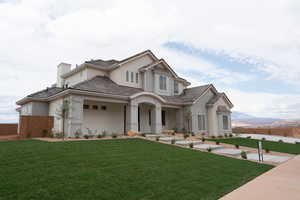 View of front of property featuring a porch, a chimney, a tile roof, a front yard, and stucco siding
