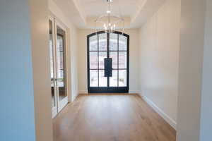 Doorway to outside with a chandelier, french doors, hardwood / wood-style flooring, and a tray ceiling