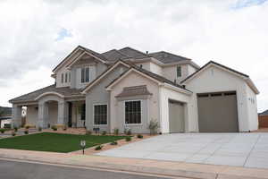 View of front of home featuring concrete driveway, an attached garage, a front yard, and stucco siding