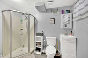 Full bath featuring a stall shower, vanity, and a textured ceiling