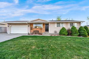 Ranch-style house with concrete driveway, a front lawn, an attached garage, and brick siding