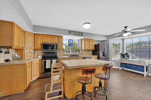 Kitchen with tile counters, stainless steel appliances, a ceiling fan, backsplash, and a center island