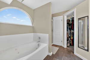 Bathroom with a jetted tub, a shower stall, and a walk in closet
