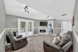 Living area with french doors, a textured ceiling, track lighting, and a glass covered fireplace