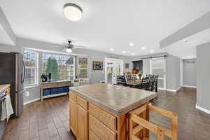 Kitchen featuring a barn door, tile counters, dark wood-type flooring, a ceiling fan, and stainless steel appliances