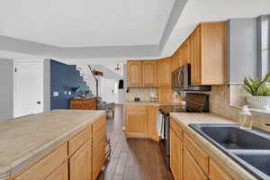 Kitchen with stainless steel electric stove, dark wood finished floors, tile counters, and tasteful backsplash