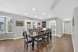 Dining room with a barn door, french doors, a textured ceiling, wood finished floors, and recessed lighting