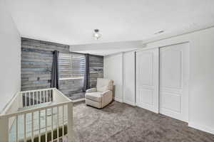Bedroom with carpet floors, a nursery area, a closet, and a textured ceiling