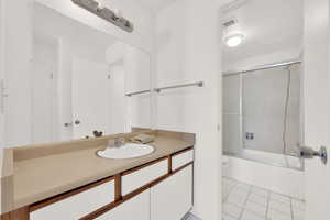 Bathroom with vanity, enclosed tub / shower combo, and light tile patterned flooring