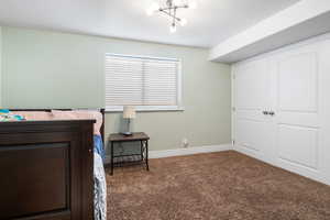 Carpeted bedroom featuring a chandelier, a closet, and a textured ceiling