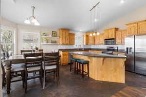 Kitchen with lofted ceiling, stainless steel appliances, a kitchen bar, a center island, and decorative backsplash
