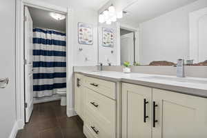 Full bathroom featuring double vanity, dark tile patterned floors, and a textured ceiling