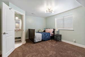 Bedroom with dark colored carpet, a chandelier, and a textured ceiling