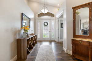 Foyer entrance with dark wood-type flooring, vaulted ceiling, plenty of natural light, and arched walkways