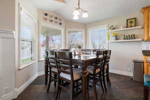 Dining area featuring hanging lights, stone tile floors, and vaulted ceiling