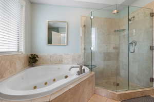 Bathroom with a stall shower, a jetted tub, and tile patterned flooring