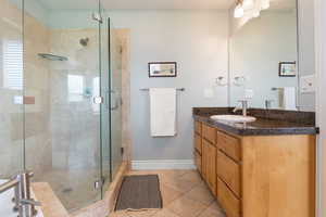 Full bathroom with vanity, a stall shower, and light tile patterned floors