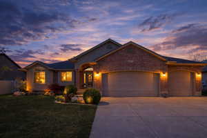 Ranch-style house featuring an attached garage, concrete driveway, brick siding, and a front yard