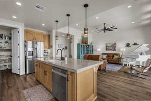 Kitchen featuring stainless steel appliances, dark wood-type flooring, light stone countertops, hanging light fixtures, and open floor plan