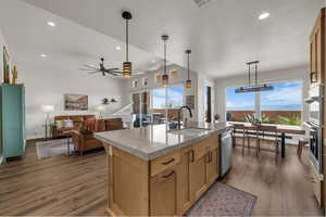 Kitchen featuring open floor plan, dark wood-style flooring, a kitchen island with sink, a ceiling fan, and stainless steel appliances