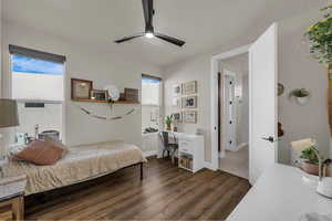 Bedroom with an office area, dark wood-style flooring, and ceiling fan