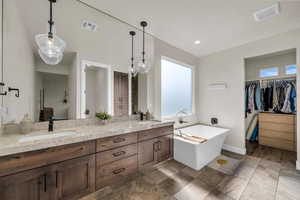 Full bath with double vanity, a walk in closet, and a freestanding bath