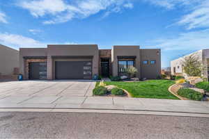 View of front of property featuring stone siding, a garage, stucco siding, and a front yard