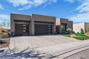 View of front of home featuring stone siding, a garage, driveway, and stucco siding