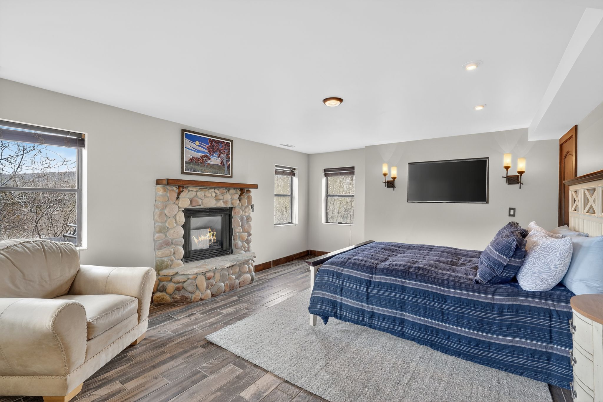 Bedroom with a stone fireplace and wood finished floors