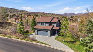 View of front of home featuring a shingled roof, a mountain view, concrete driveway, a garage, and a front yard