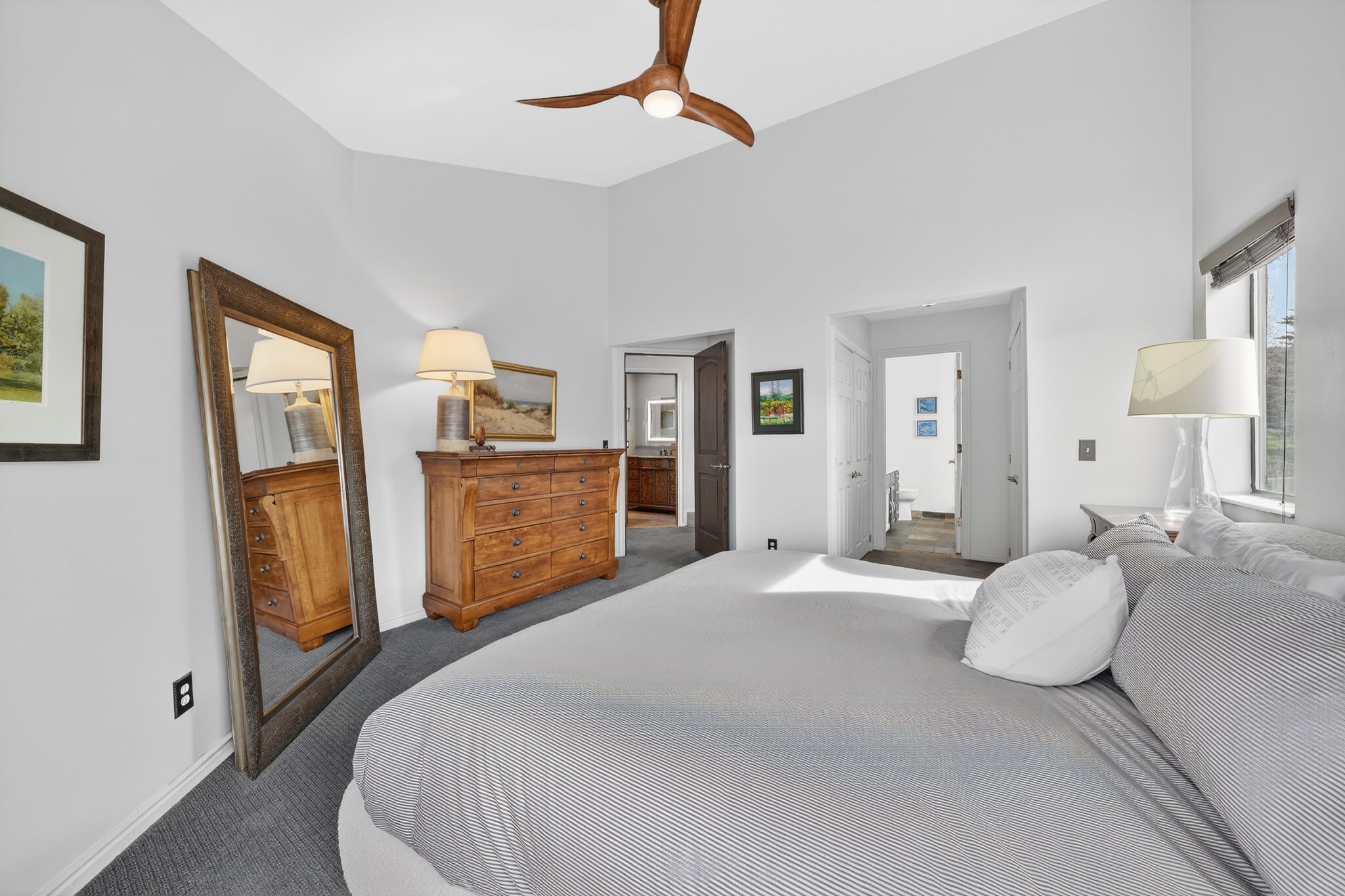 Bedroom with dark carpet, ensuite bath, ceiling fan, and a high ceiling