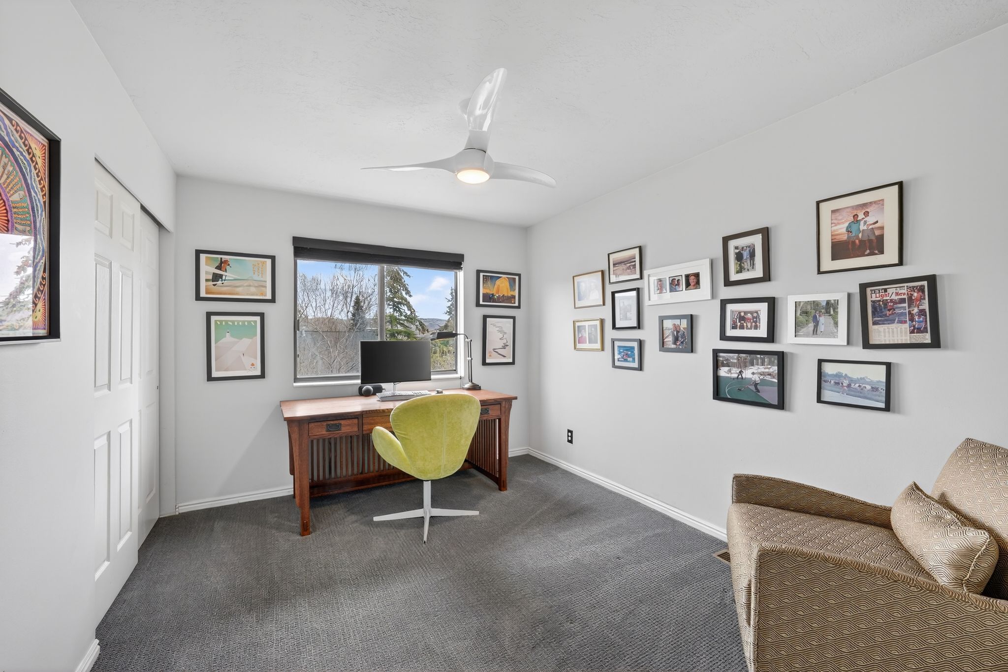 Home office featuring a ceiling fan and dark colored carpet