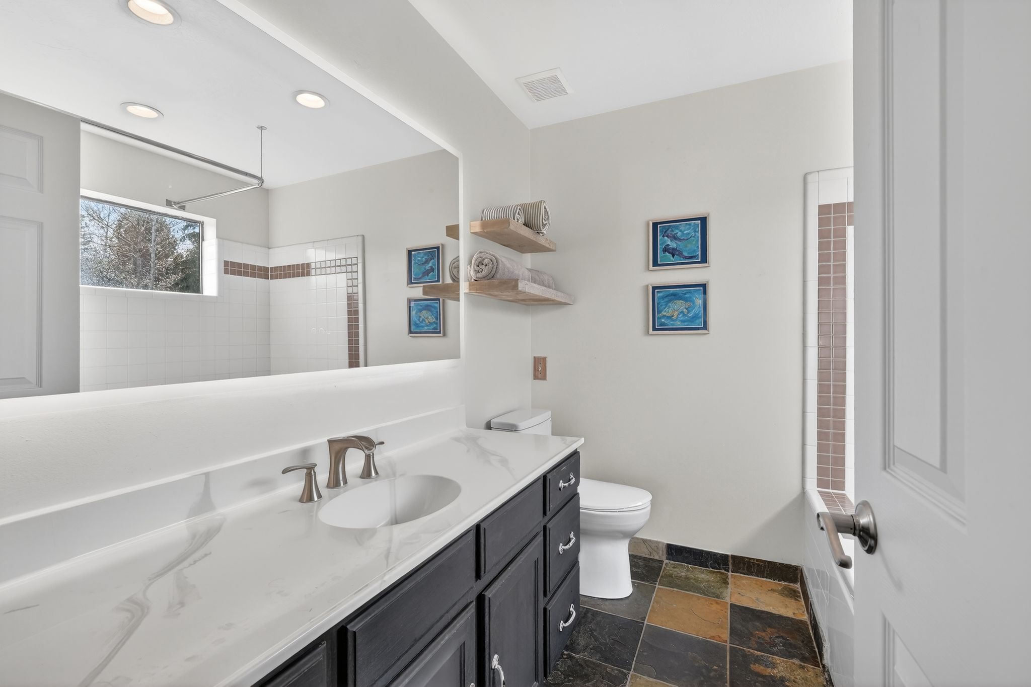 Full bath featuring vanity, a tile shower, dark stone finish floors, and recessed lighting