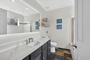 Full bath featuring vanity, a tile shower, dark stone finish floors, and recessed lighting