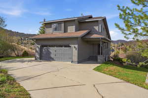 Traditional-style house featuring concrete driveway, a mountain view, a front lawn, and an attached garage