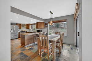 Dining space featuring stone tile flooring and recessed lighting