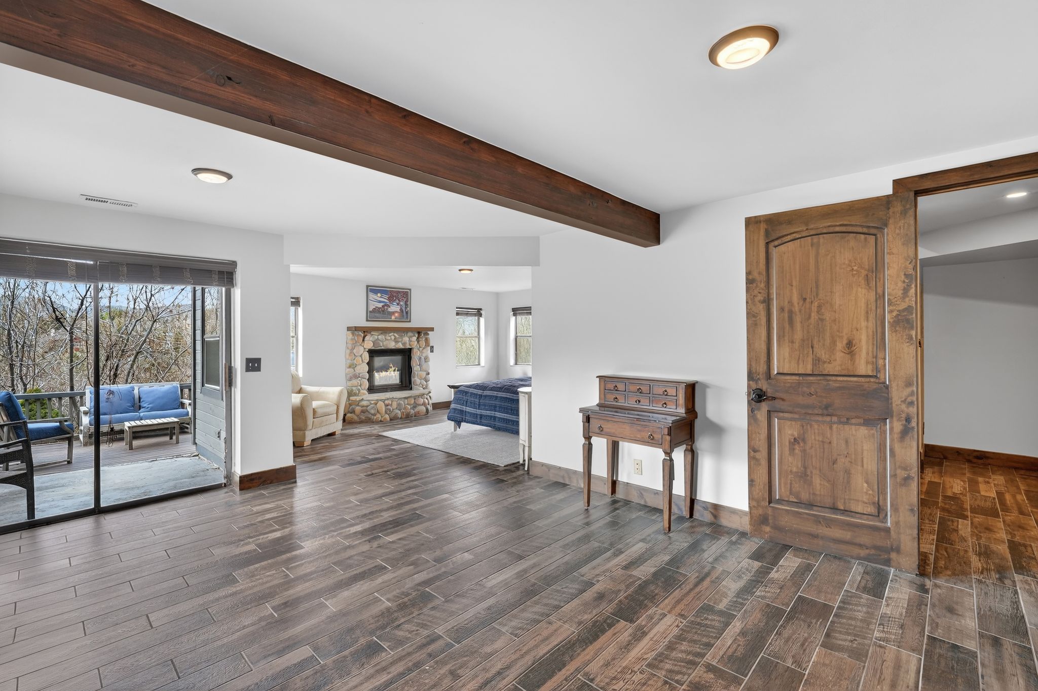 Living area with wood tiled floors, beamed ceiling, recessed lighting, and a stone fireplace