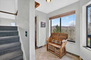 Sitting room with a textured wall, plenty of natural light, light tile patterned floors, and a mountain view