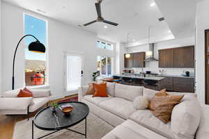 Living area with a ceiling fan, light wood-type flooring, recessed lighting, and a high ceiling