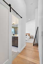 Hallway featuring a barn door, light wood finished floors, and recessed lighting