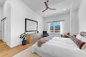 Bedroom featuring a mountain view, light wood-style flooring, vaulted ceiling, ceiling fan, and recessed lighting