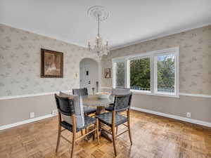 Dining area with arched walkways, suspended lighting, parquet flooring, and wainscoting