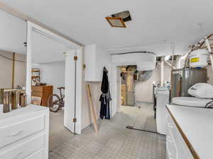 Kitchen featuring white cabinets, water heater, light countertops, washer and clothes dryer, and light floors