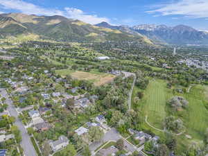 Aerial perspective of suburban area featuring a mountain backdrop and a golf course