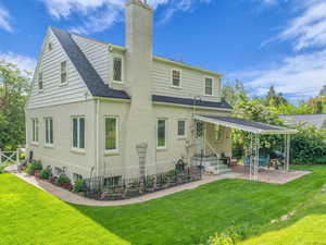 Rear view of property with a patio, brick siding, a shingled roof, and a chimney