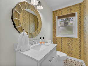Bathroom with vanity, ornamental molding, and wallpapered walls