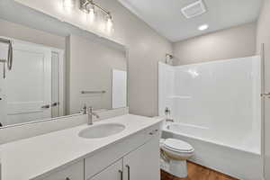 Full bath featuring vanity, dark wood-style floors, and shower / tub combination