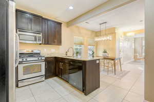 Kitchen featuring stainless steel appliances, a peninsula, dark wood finish cabinetry