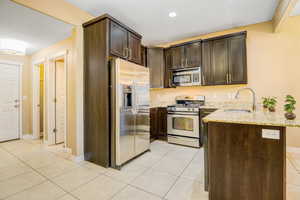 Kitchen featuring a peninsula, dark wood finish cabinetry, stainless steel appliances